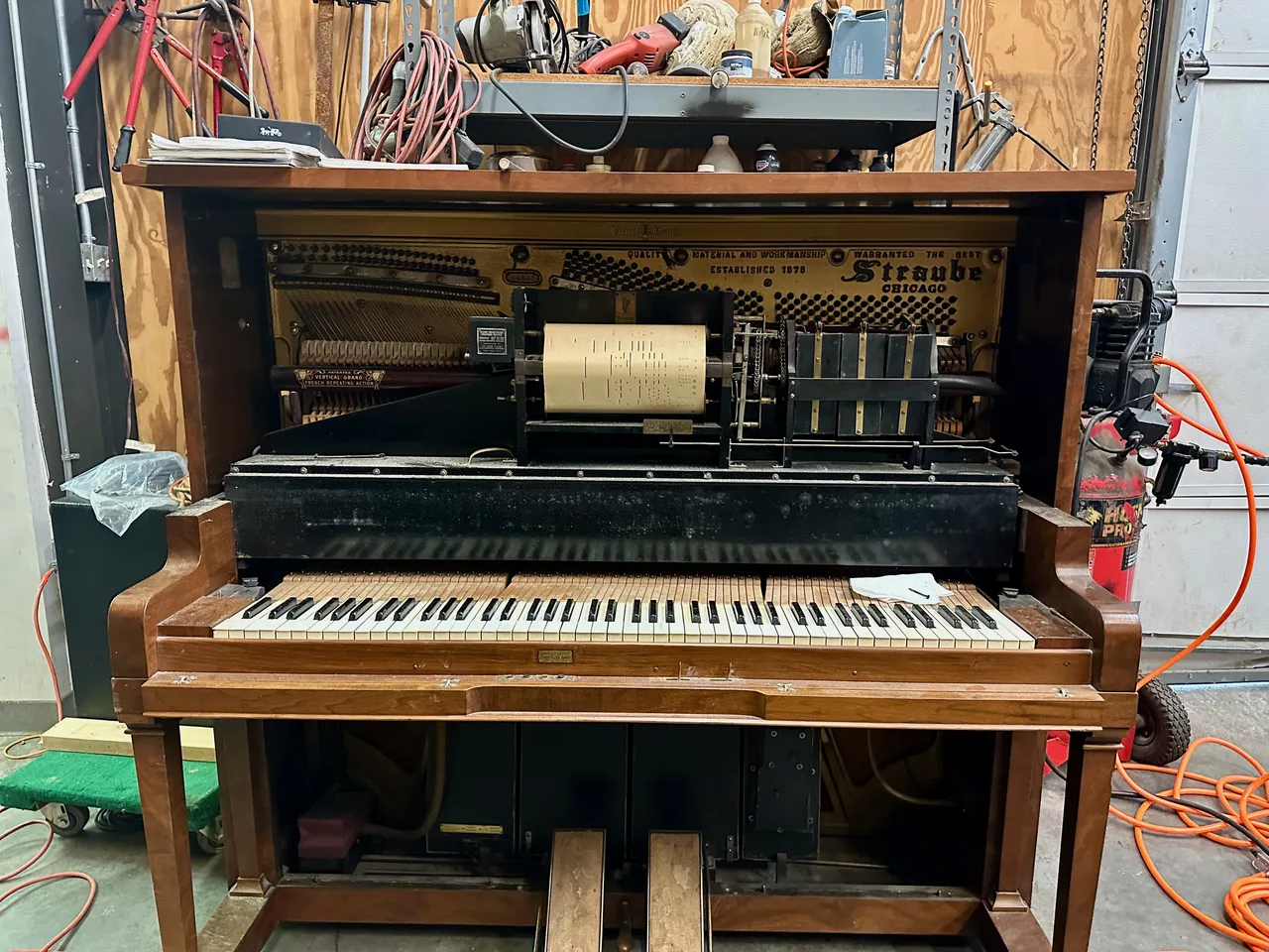 An opened and partially dismantled player piano in a workshop